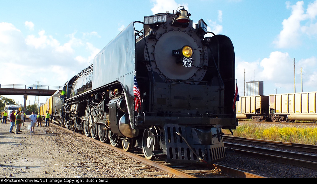 Still servicing, while a coal drag drifts past.